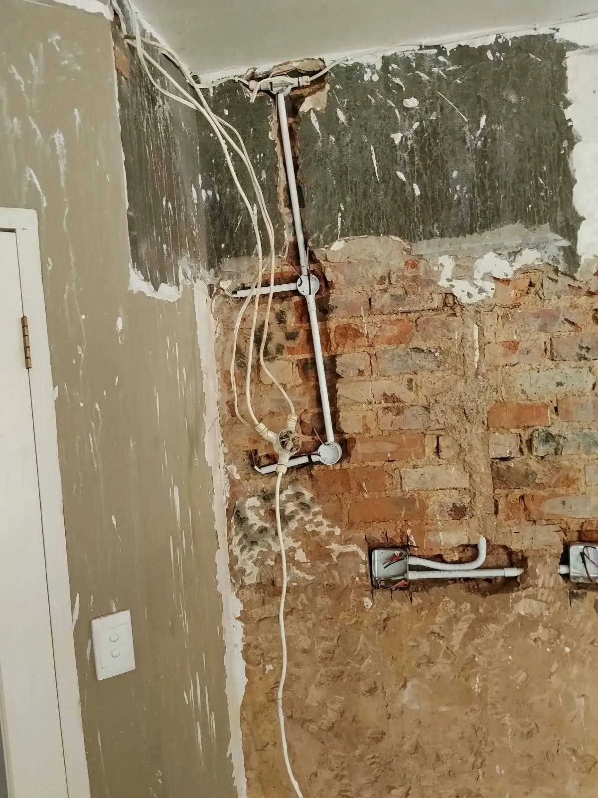 Electrical conduit, junction boxes and wall boxes chased into an exposed brick wall