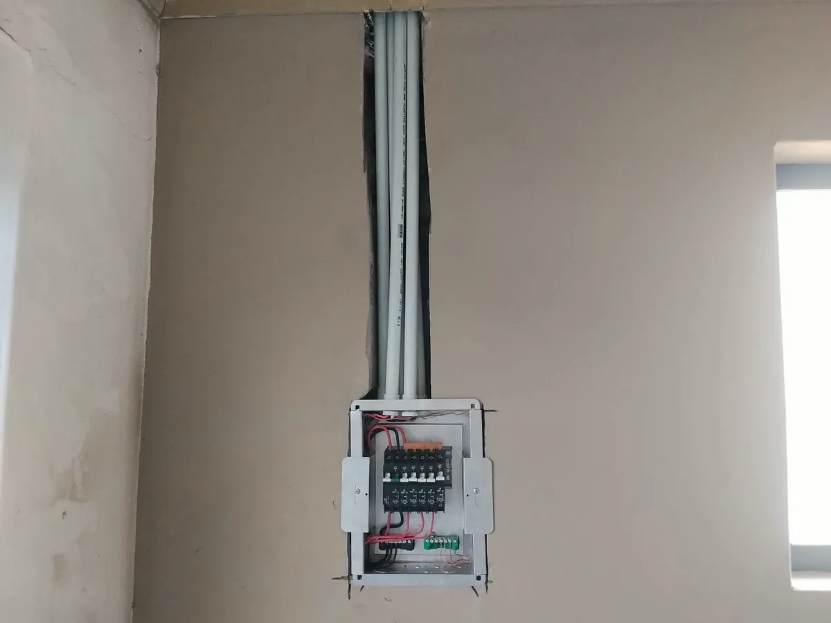 New distribution board with circuit breakers wired in and grey conduits running up a chased wall