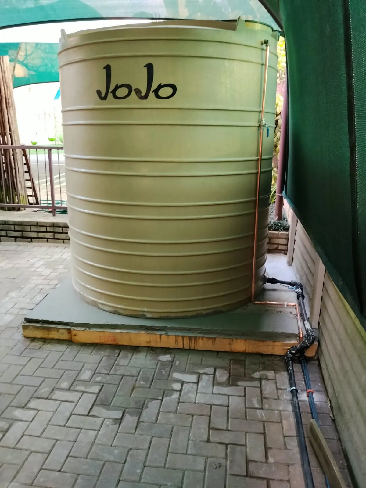 Large JoJo water tank on a new concrete base with copper and plastic pipework