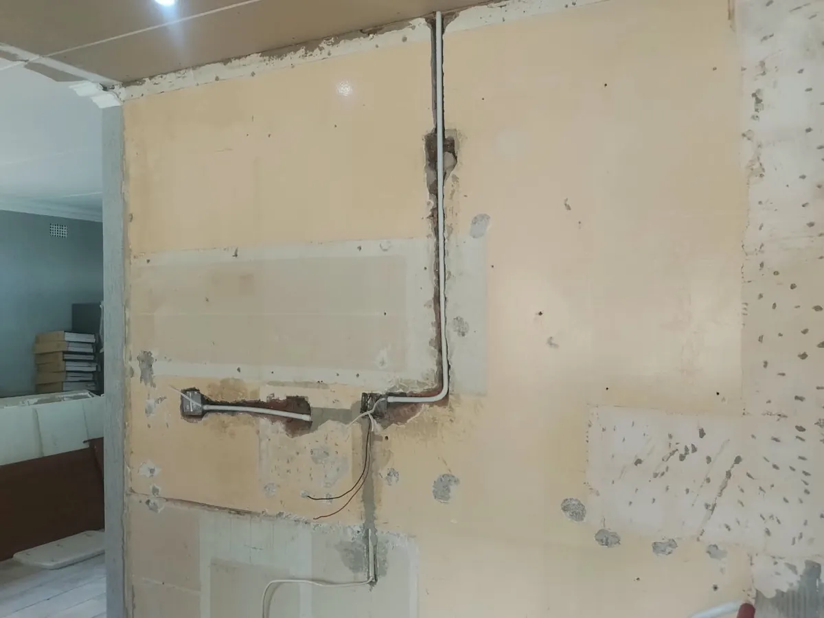 Kitchen wall stripped during a renovation, with new electrical conduit chased in below a new ceiling
