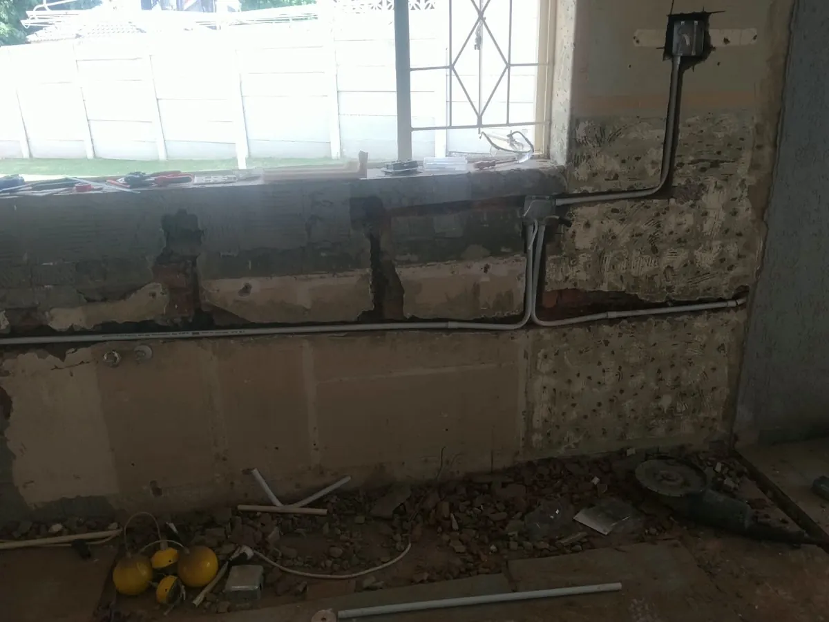 Electrical conduit run along a stripped kitchen wall below a window
