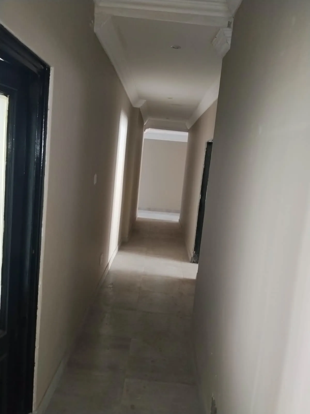 Passage with painted walls, white cornices and a tiled floor