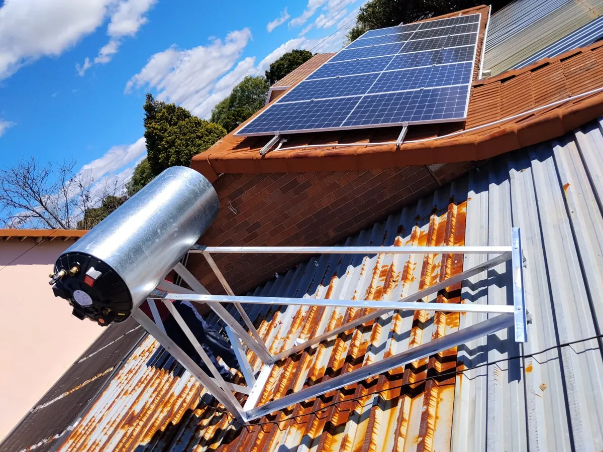 Solar geyser tank on an aluminium stand on a roof beside solar panels