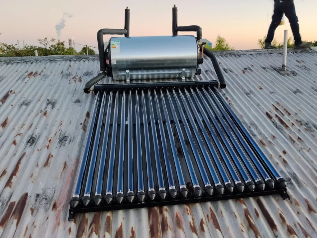 Solar geyser and evacuated tubes mounted on a corrugated roof at dusk