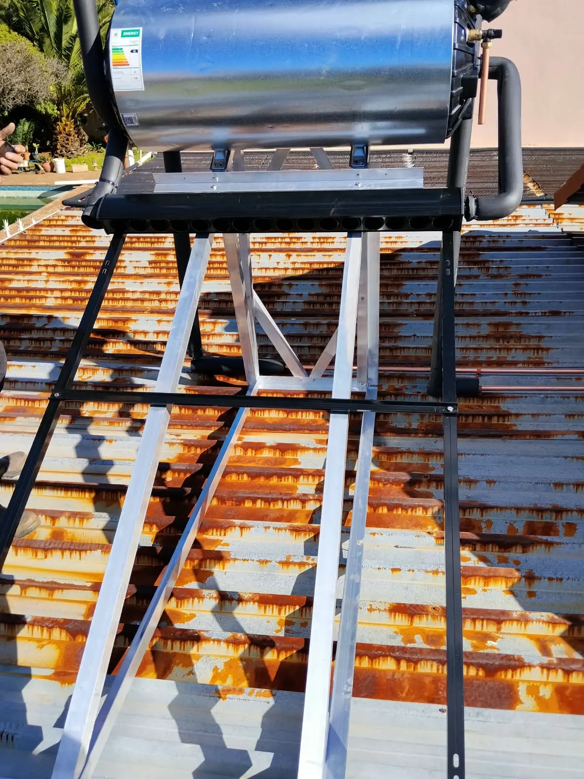 Aluminium stand for a solar geyser being assembled on a corrugated roof