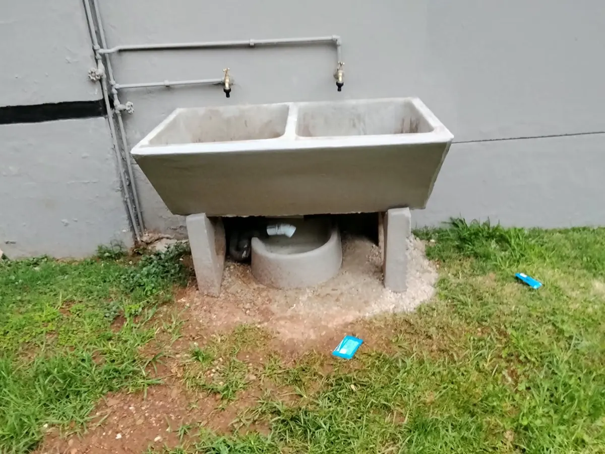 Concrete double wash trough with two taps and a drain outside a house