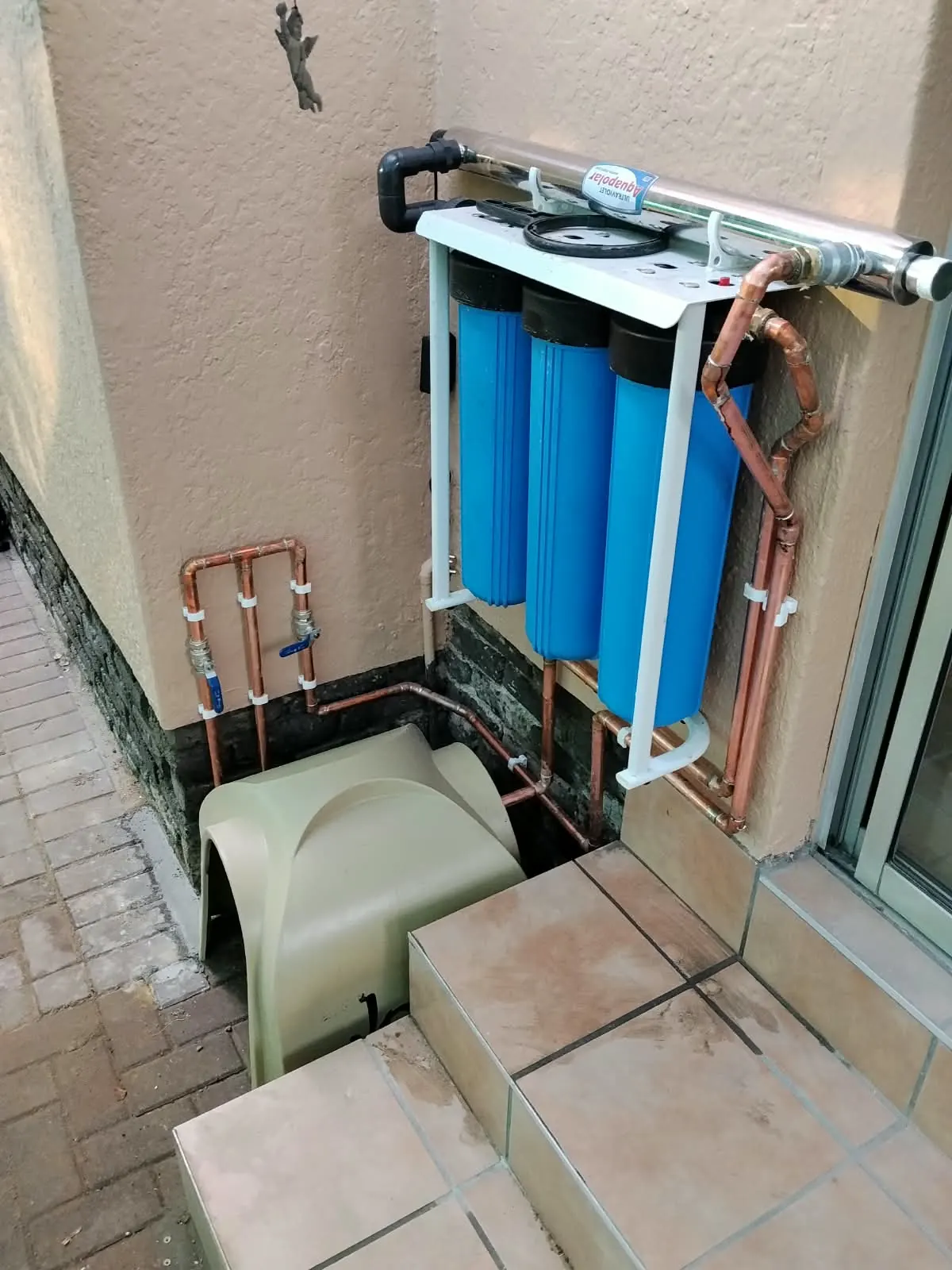 Water filtration unit with UV steriliser plumbed in copper next to a covered pump