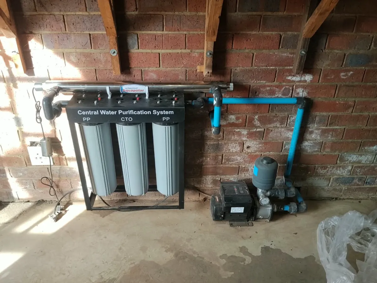 Central water purification system with UV unit and a booster pump on a brick wall