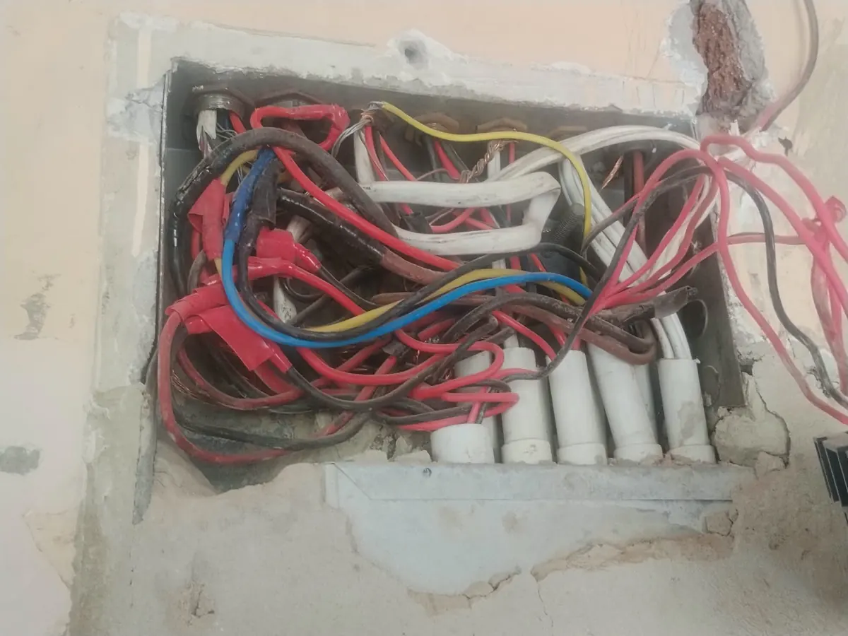 Tangled wiring inside a wall-mounted electrical box before repair